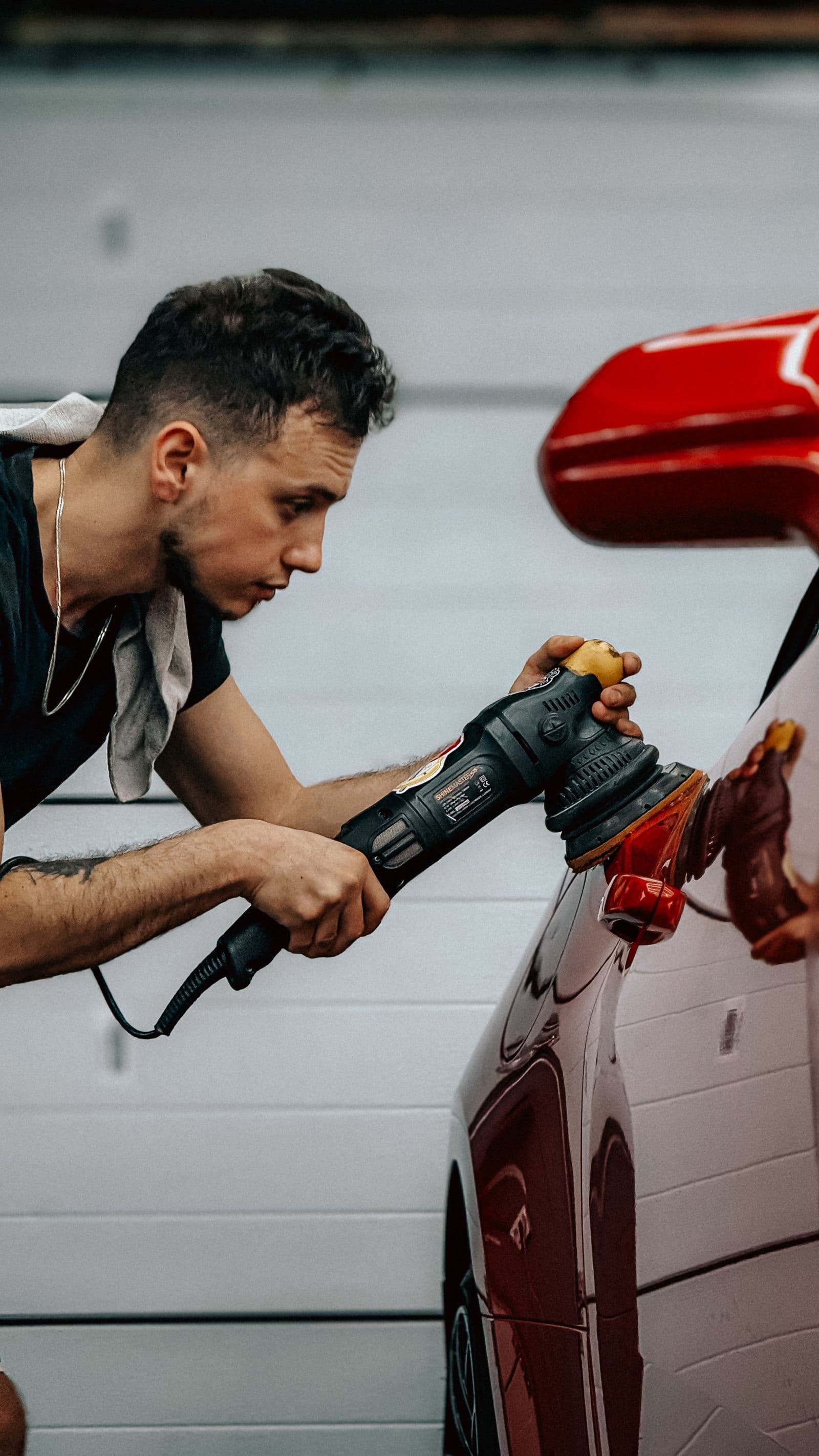 Machine polisher refining paint on a red car