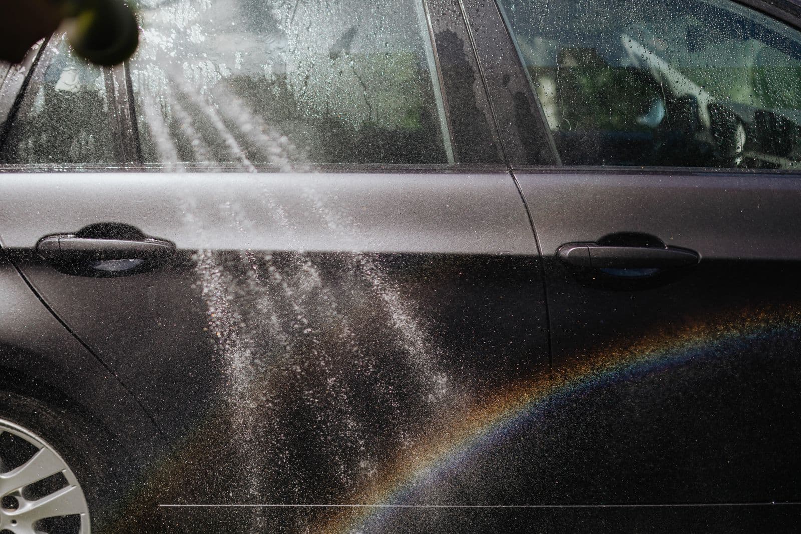 Water spraying off a car in sunlight, the runoff a hose wash creates