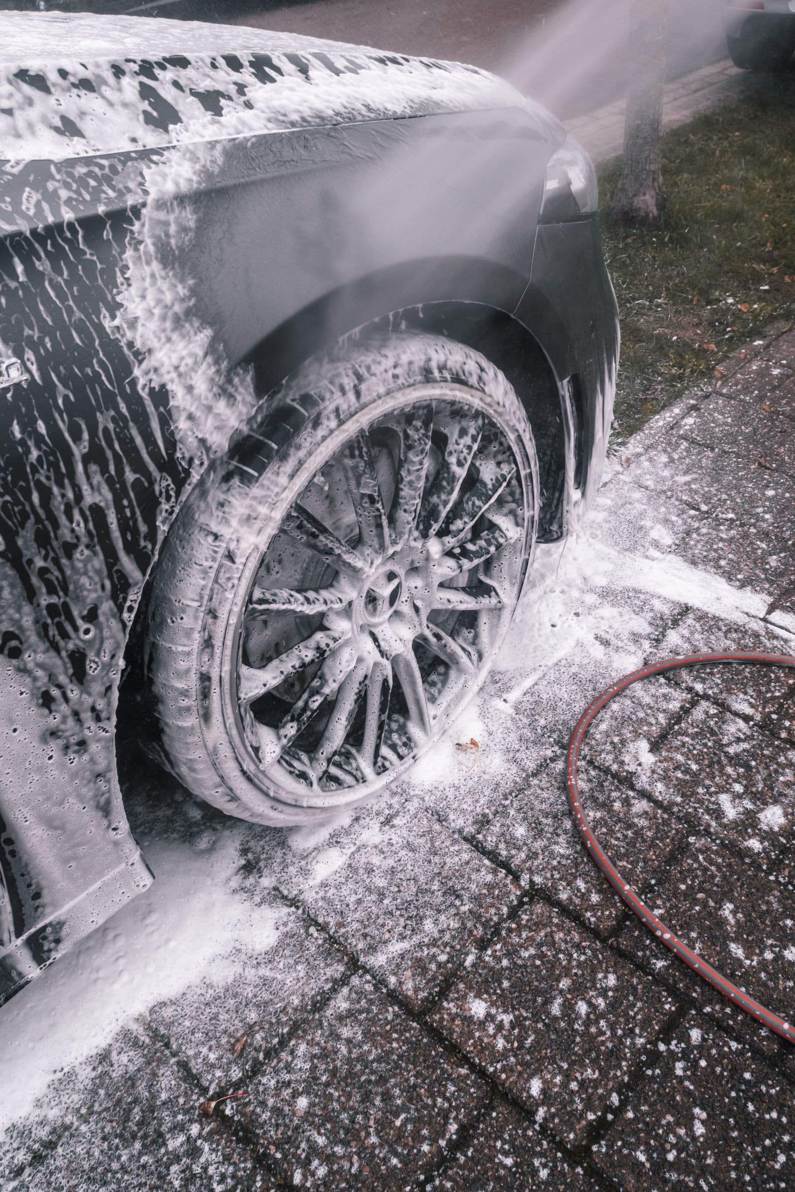 Alloy wheel covered in cleaner during a decontamination step
